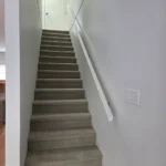 Carpeted staircase with white handrail and clean walls as part of modern interior renovation