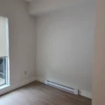 Corner room with fresh paint, baseboard heater, and wood flooring after modern interior renovation