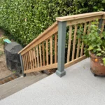 Wood deck stairs with new railing, gray posts, and planter during deck railing renovation