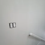 Stairwell wall with new paint, handrail, and updated light switches in modern interior renovation