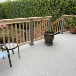 Updated deck with wood railing, gray posts, planters, and seating after deck railing renovation