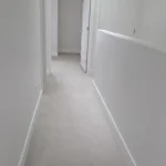 Bright hallway with skylight, new carpet, and white doors in modern interior renovation