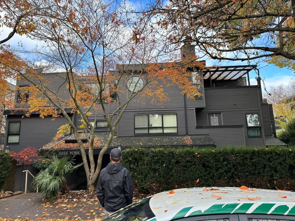 Three-story building with modern dark exterior siding surrounded by autumn trees—example of large-scale exterior painting project.