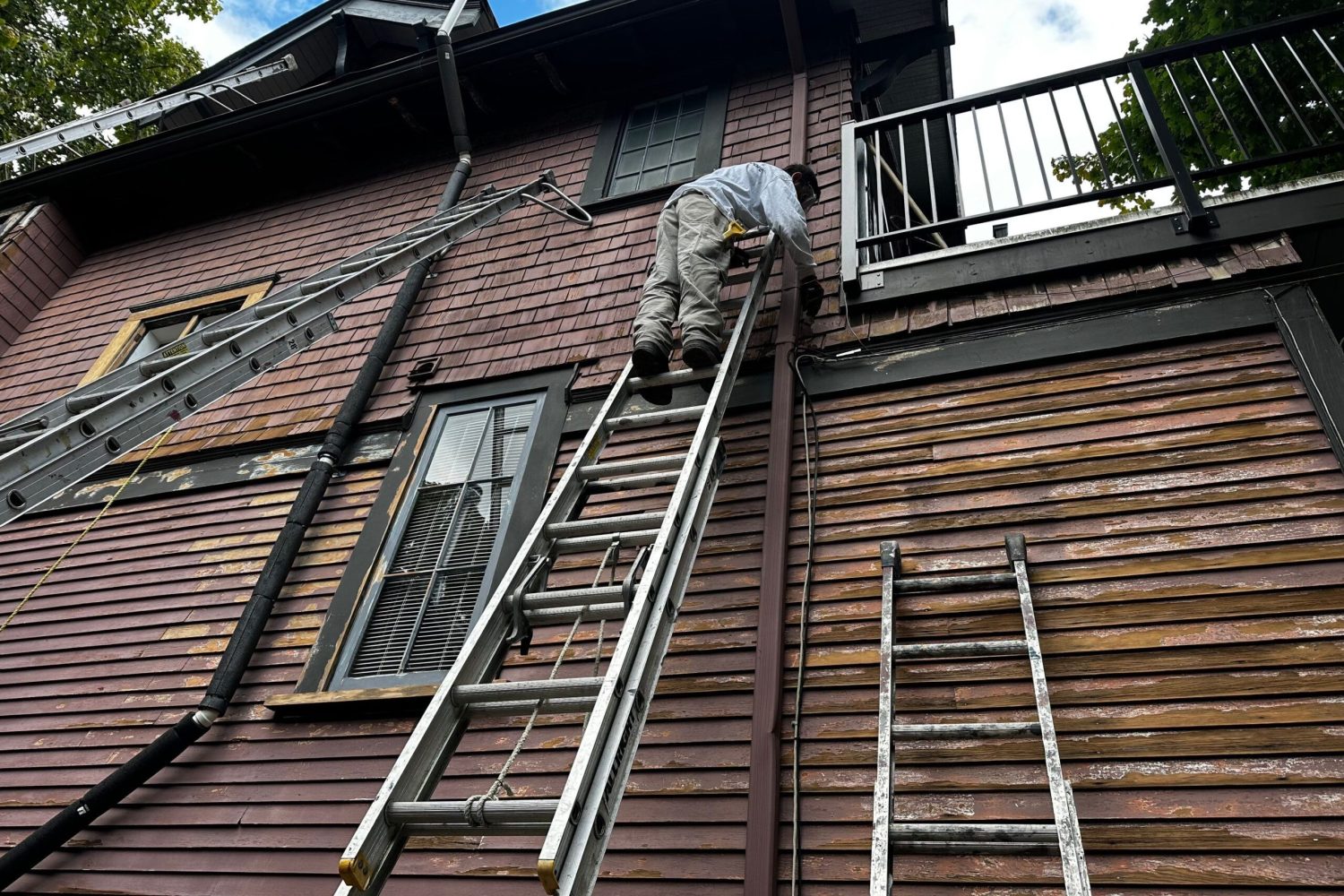 Siding repairment and painting on a ladder.