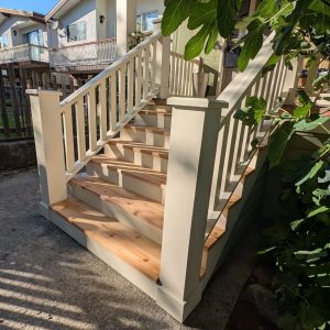 White wooden staircase with green plant an example of detailed exterior carpentry