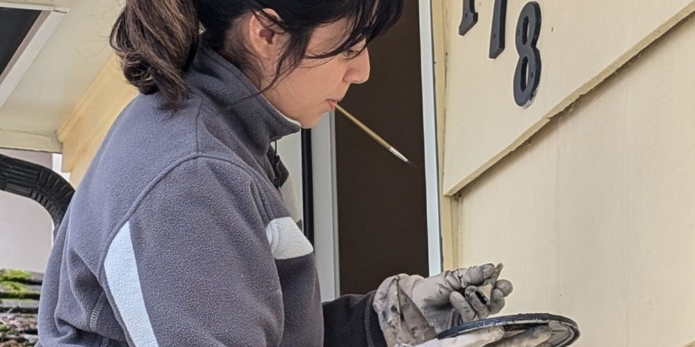 A painter is painting a house number with extra precision.