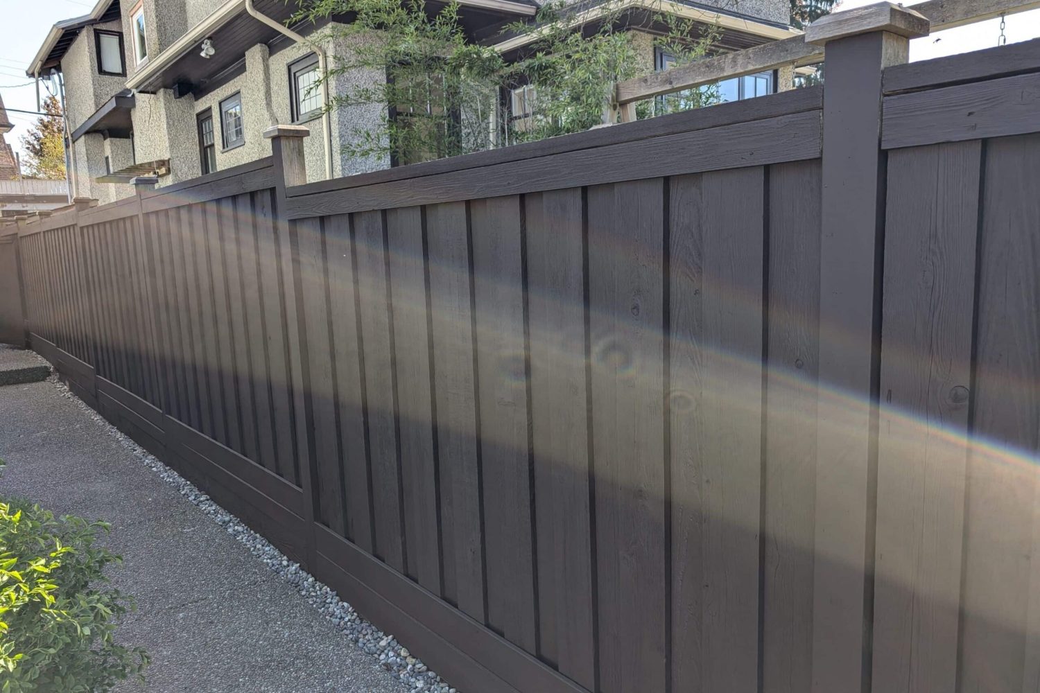 Brown wooden fence with black trim, repaired and reinforced for durability
