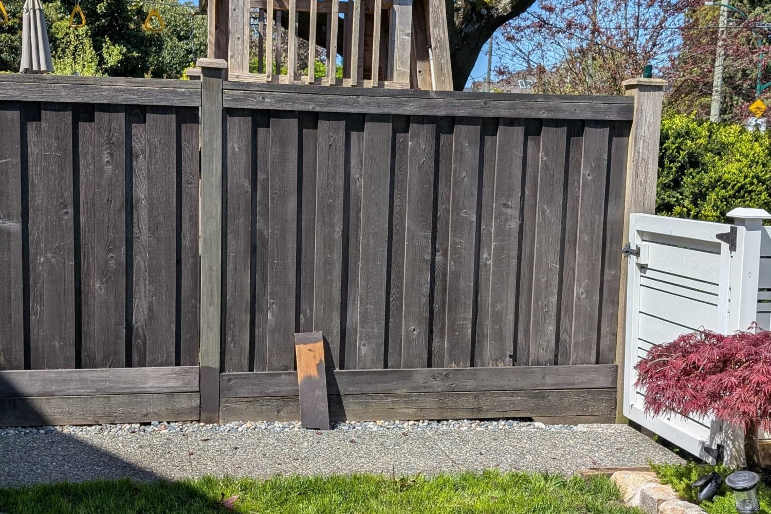 Wooden fence with gate and small garden, repaired and freshly stained