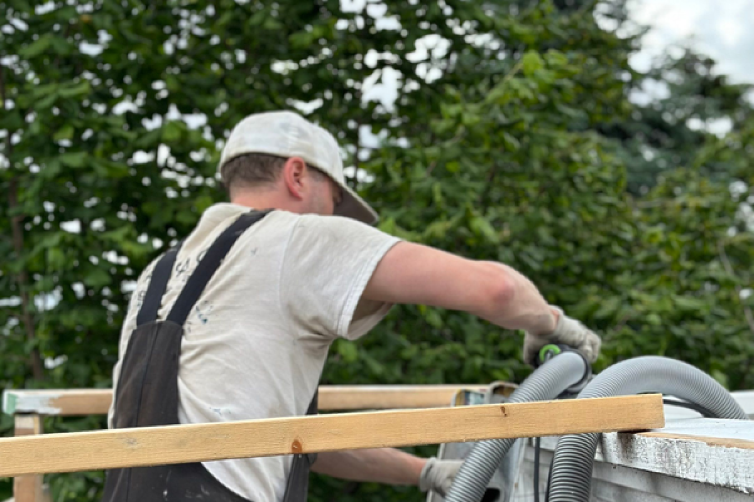 A carpenter is doing a fence job with a vacuum cleaner.