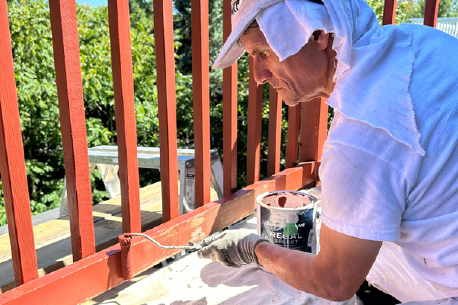 Painter is painting a railing in a red colour.