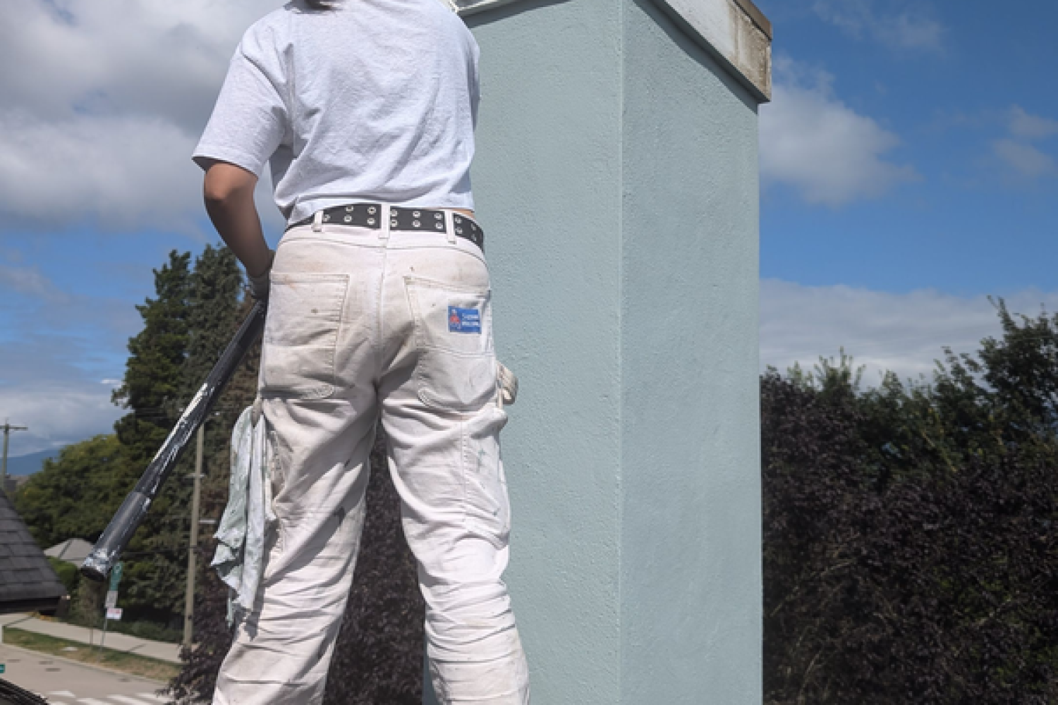 Painter is painting a metal chimney rain cap.